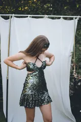 Vestido corto negro con diseño cut-out en la cintura, estilo strapless y ruedo decorado con flecos largos.