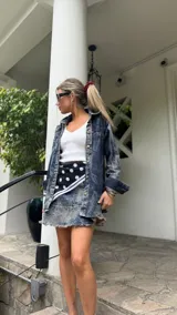 Falda corta de denim con lavado ácido (acid wash) y ruedo desflecado. Presenta un corte acampanado y cierre metálico en el costado.