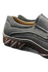 Mocasín de hombre estilo casual, color gris, confeccionado en material sintético con costuras blancas visibles y suela robusta de goma.