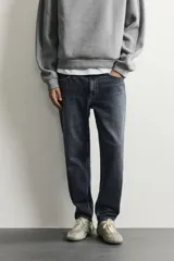 Jeans de corte slim cropped confeccionados en denim de algodón rígido con efecto lavado. Presentan tiro medio, cierre frontal con cremallera y botón, y diseño clásico de cinco bolsillos.