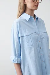 Camisa blanca de algodón con diseño utilitario y calce relajado. Presenta dos bolsillos frontales de estilo cargo con tapa y costuras a contratono.