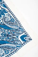 Bandana cuadrada de color blanco con diseño ornamental en tonos de azul, con estampado paisley y detalles geométricos.