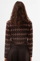 Camiseta de manga larga con cuello polo y cierre frontal parcial, confeccionada en tejido de punto con estampado geométrico en tonos azul, bordó y celeste.