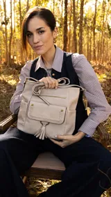 Bandolera negra de cuero sintético con cierre superior y correa larga regulable. Tiene bolsillo frontal con tapa y broches magnéticos, detalle de trenza artesanal, división interna, bolsillos internos y bolsillos laterales tipo ojal.