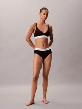 Corpiño de lactancia Calvin Klein negro con copas triangulares ligeramente forradas, tirantes finos ajustables con clip de apertura y banda elástica inferior blanca con el logo de la marca.