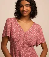 Enterito corto color rosa con estampado floral, escote en pico, botones y mangas cortas holgadas.