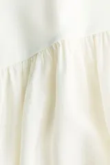 Vestido midi blanco sin mangas con cuello redondo, cuerpo entallado en punto acanalado de algodón y falda amplia con costura fruncida en diagonal.