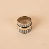 Anillo ancho de diseño mixto, compuesto por una banda central lisa de oro amarillo flanqueada por dos bandas laterales de plata 925 con acabado martillado.