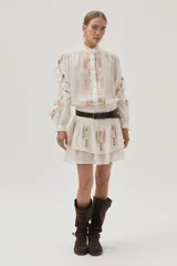 Falda corta de color blanco con diseño de doble volado y delicados bordados en tonos suaves que aportan movimiento y estilo.