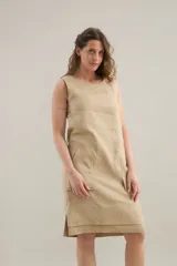 Vestido midi de lino color beige, de silueta relajada, escote redondo, sisas amplias y bolsillos delanteros aplicados.