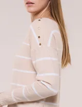 Buzo de punto fino beige con rayas horizontales blancas, escote bote y detalles de botones dorados en el hombro.
