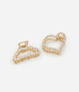 Set de dos pinzas para el pelo doradas, una con forma de media luna y otra con forma de corazón. Ambas están decoradas con strass y perlas artificiales.