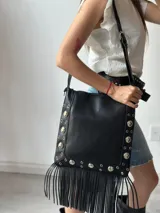 Bolso tipo tote bag color negro, con flecos largos y apliques metálicos.