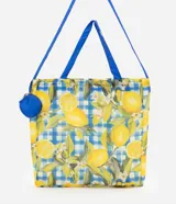 Bolsa plegable con estampa de limones y patrón de cuadros azules y blancos. Cuenta con asas largas de color azul y un monedero redondo colgante con diseño de limón.