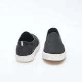 Zapatillas bajas slip-on negras de malla con suela blanca.