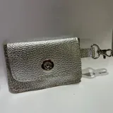 Tarjetero pequeño de cuero sintético plateado con cierre de broche a presión y gancho metálico.