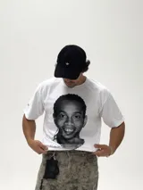 Remera blanca de corte boxy y diseño oversize, con estampa fotográfica frontal en blanco y negro del futbolista Ronaldinho.