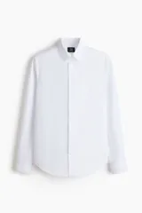 Camisa blanca de corte slim fit, con cuello inglés, tapeta clásica, canesú en la espalda, mangas largas con puños abotonados y bajo levemente redondeado. Confeccionada en tela de fácil planchado.