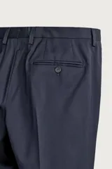 Pantalón de traje regular fit negro, confeccionado en lana italiana, con bolsillos laterales, bolsillos traseros de vivo con botón y cierre frontal de cremallera y botón.