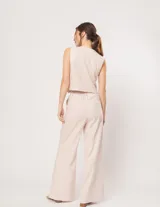 Pantalón negro de lino, tiro alto, corte palazo, con elástico en la pretina trasera, cierre delantero y broche interno. Tiene bolsillos laterales, dobladillo invisible y tajos a los costados.