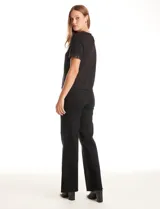 Blusa negra de manga corta con cuello redondo y puños decorados con ribetes de lentejuelas brillantes. Confeccionada en tejido suave y fluido, presenta una silueta recta y cierre de ojal con botón en la espalda.