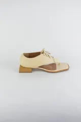 Sandalias de cuero color beige con diseño de ojota acordonada en el empeine, puntera cuadrada y taco bajo cuadrado.