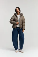 Campera puffer color topo con capucha, cierre frontal y bolsillos laterales con cierre. Presenta un diseño acolchado con volumen y puños elásticos.