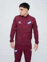 Campera deportiva Umbro del Club Nacional de Football, modelo Grok, en color bordó con diseño estampado sutil. Cuenta con cierre frontal completo, cuello alto y bolsillos laterales.