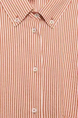 Camisa de cuello solapa y manga larga con estampado de rayas verticales. Presenta un bolsillo de plastrón en el delantero, cierre frontal con botones y detalle de botones en la espalda. Su diseño cuenta con un bajo asimétrico y aberturas laterales.