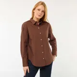 Camisa de manga larga de popelina color marrón, con cuello camisero, cierre frontal de botones y puños anchos.