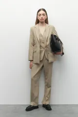 Blazer gris oscuro de corte clásico, con solapas de muesca, cierre con dos botones a tono, bolsillos de solapa decorativos y mangas largas.