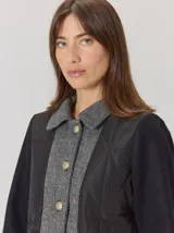 Campera de diseño híbrido con frente acolchado en color tostado, solapas y cuello en tejido de lana con patrón de cuadros tipo príncipe de gales, y mangas en paño de lana color azul marino. Cuenta con cierre frontal de botones.