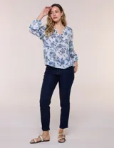 Blusa holgada de rayón y poliéster, marca Zac & Rachel, con estampado floral en tonos azules sobre fondo blanco. Posee escote en V con muesca central, mangas largas abullonadas con inserción de puntilla y puños elastizados.