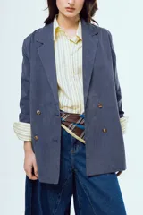 Blazer de corte oversize color azul, con solapas clásicas, cierre de doble botonadura frontal y bolsillos ribeteados.