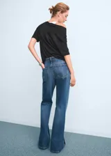 Pantalón de jean tiro medio con corte recto y largo, confeccionado en tejido de algodón. Cuenta con cierre de cremallera y botón, trabillas para cinturón, diseño de cinco bolsillos y aberturas laterales en el bajo.