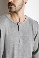 Remera de manga larga gris de tejido waffle, con cuello redondo y cierre frontal parcial de tres botones.