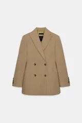 Blazer entallada de Zara Woman Collection, confeccionada en tejido con lana. Presenta cuello con solapas de muesca, cierre frontal cruzado con botones y manga larga con detalle de botones en los puños.