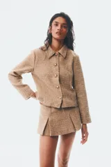 Chaqueta corta de tejido texturizado en color tostado, con cuello camisero, cierre frontal de botones metálicos dorados y diseño entallado con costuras moldeadoras.