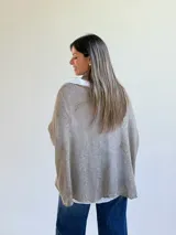 Sweater de punto color visón con diseño superpuesto, que incluye una bufanda integrada y detalles de encaje floral en el frente. Presenta mangas tres cuartos con puños abotonados y un corte holgado.