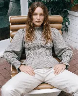 Blusa de algodón con patrón a cuadros vichy en tonos gris y blanco, de corte ajustado en el torso con diseño fruncido elástico, cuello alto y mangas abullonadas con puños ajustados y volados.