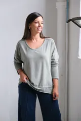 Remera de algodón color verde seco, con cuello redondo, mangas largas y corte holgado con dobladillo inferior.