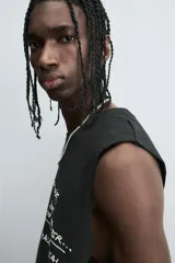 Camiseta sin mangas (tank top) negra, corte boxy fit, con cuello redondo y sisa con acabado irregular. Presenta un estampado frontal con texto manuscrito en verde y blanco que dice: "I look cool online, but offline I'm even better... Chase real likes!".