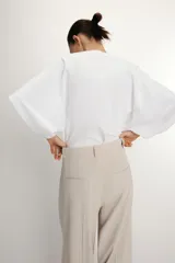 Camiseta blanca de manga corta con corte oversize y cuello redondo. El diseño presenta mangas amplias tipo capa que caen desde el hombro.