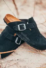 Zuecos negros con hebilla metálica ajustable.