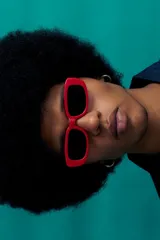 Lentes de sol de montura gruesa color rojo vibrante, con forma rectangular y esquinas redondeadas. Poseen cristales oscuros con protección UV.