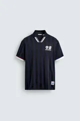 Polo de corte relajado confeccionado en tejido técnico, con diseño de rayas verticales en tonos azul marino y negro. Presenta cuello solapa con abertura frontal y detalles de rib en contraste en cuello y mangas. Incluye estampado frontal con el número 98 y la inscripción France, además de una etiqueta aplicada en el ruedo inferior.