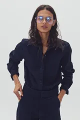 Camisa de denim azul marino con cuello clásico, mangas largas con puños abotonados y cierre frontal con botones.