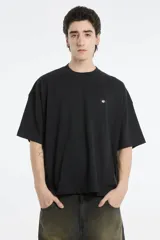 Remera negra de corte amplio con cuello redondo y logo pequeño en el pecho.