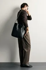 Bolso tipo shopper de diseño minimalista en color negro, con dos bolsillos planos exteriores y compartimento principal con cierre magnético. Incluye un bolsillo interior y asa de hombro ajustable.
