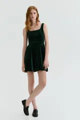 Vestido corto de velour color verde oscuro, con escote cuadrado, breteles anchos y falda acampanada con frunces laterales.